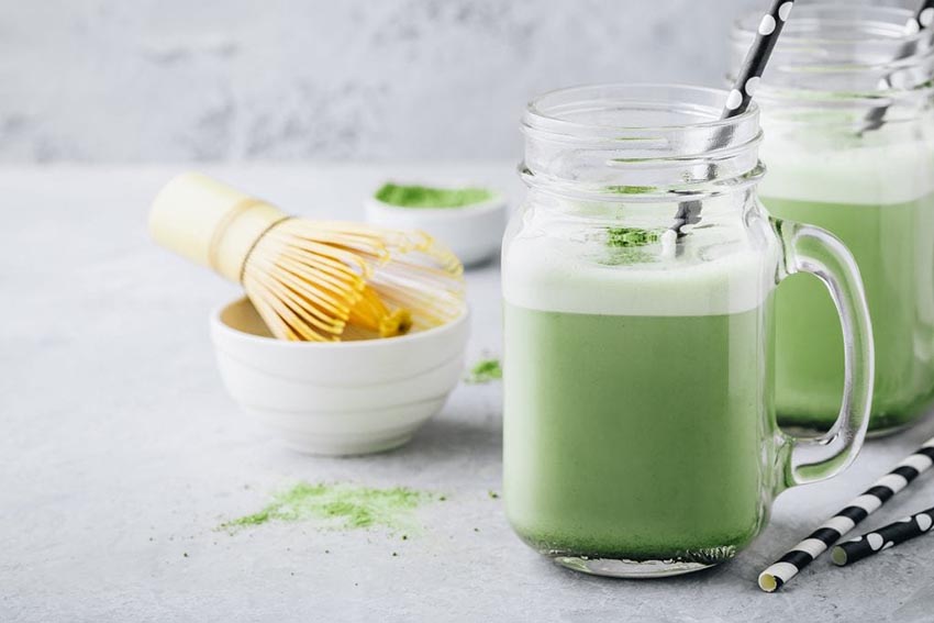 Zelený horúci matcha čokoládový nápoj v priesvitných pohároch s tmavými ozdobnými slamkami