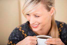 usmievajúca sa žena so šálkou kávy v rukách