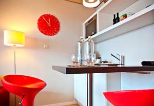 kuchynský stôl s červenými barovými stoličkami a nástennými hodinami