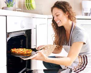 Usmievajúca žena vyberá z rúry pizzu